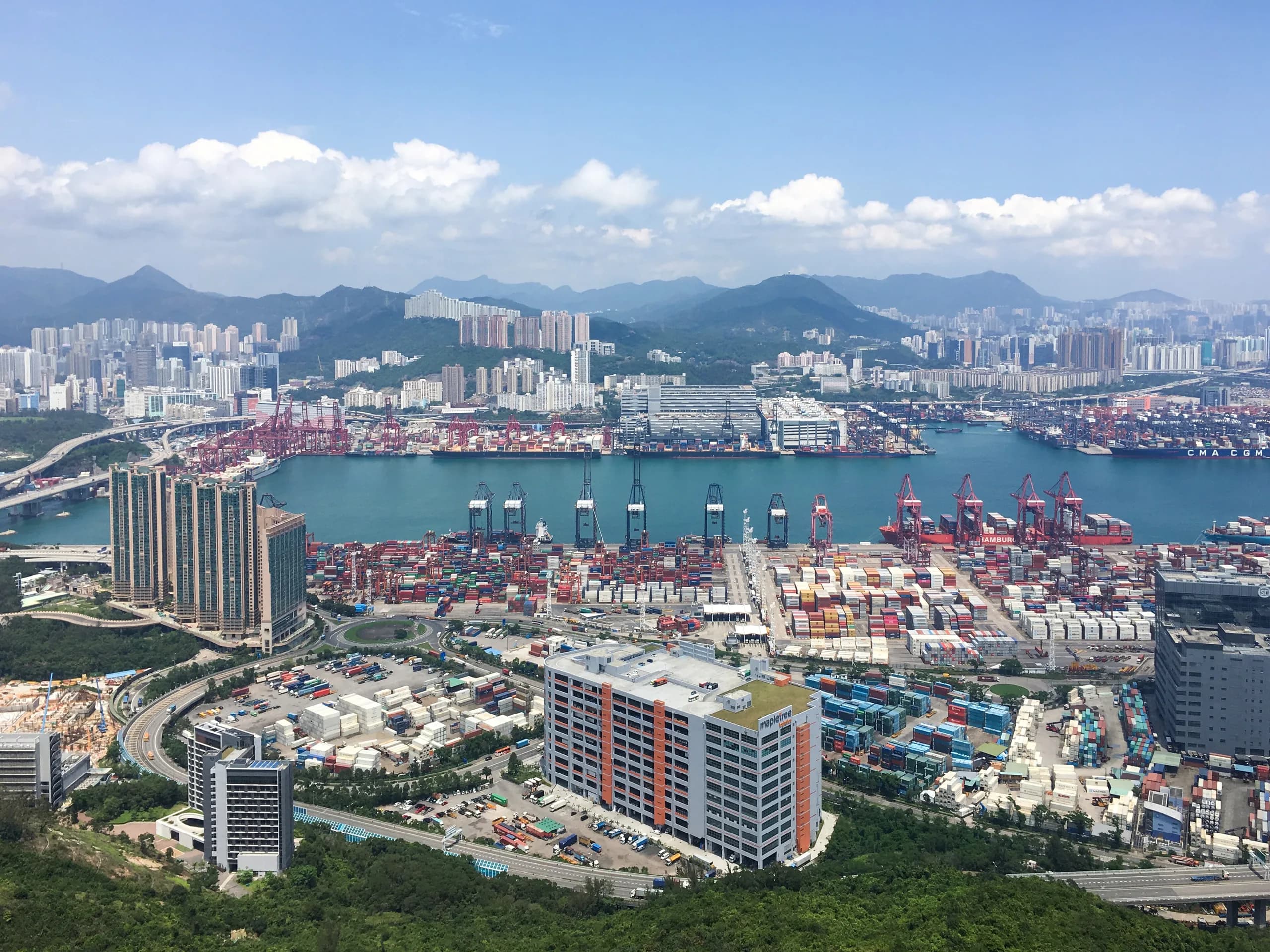 A container terminal with stacked shipping containers and cranes beside a harbour