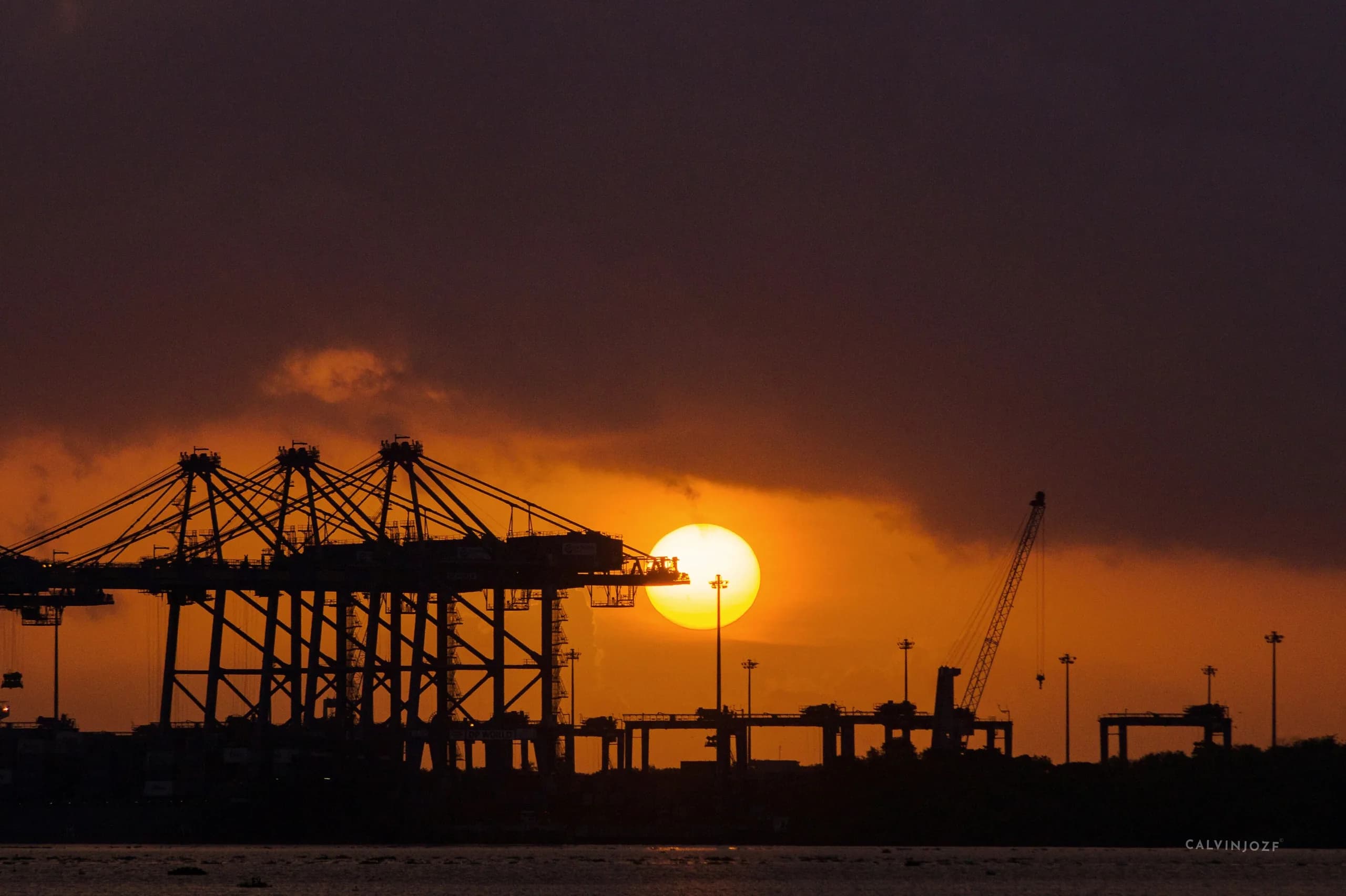 Ship-to-shore cranes at the Vallarpadam container terminal in Kochi, silhouetted against a sunset